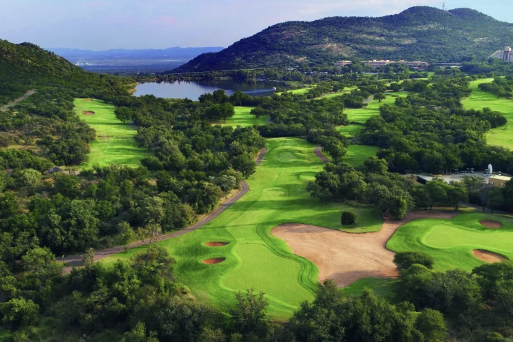 Vista panorámica del Gary Player Country Club con calles verdes, búnkeres, un lago y montañas.