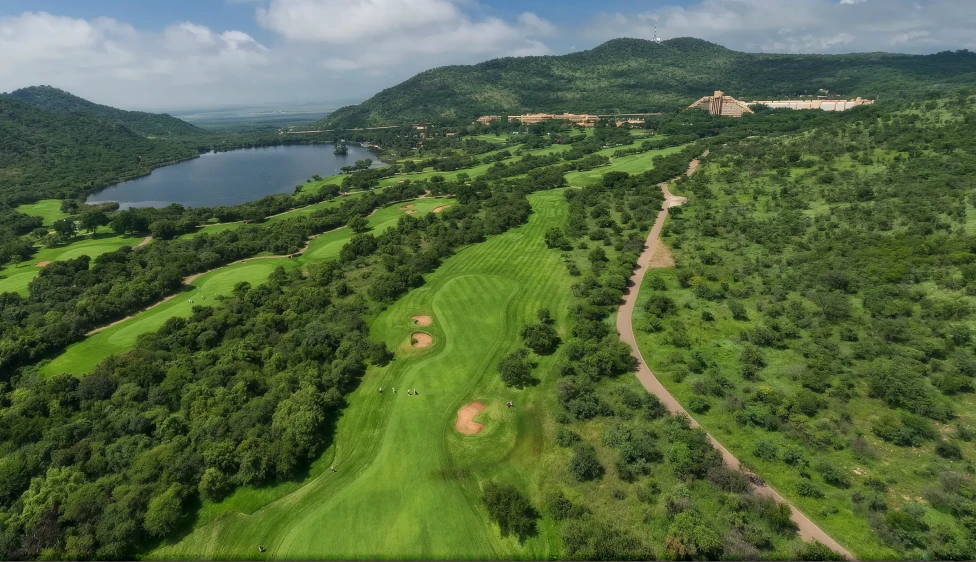 Vista aérea del Gary Player Country Club con calles verdes, búnkeres, un gran lago y montañas.