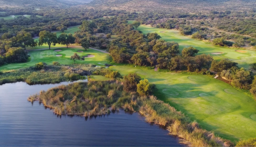 Vista aérea del Gary Player Country Club con un lago, calles verdes, greens y varios búnkeres.