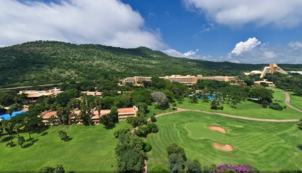 Vista aérea del Gary Player Country Club con calles verdes, búnkeres, alojamientos y montañas.