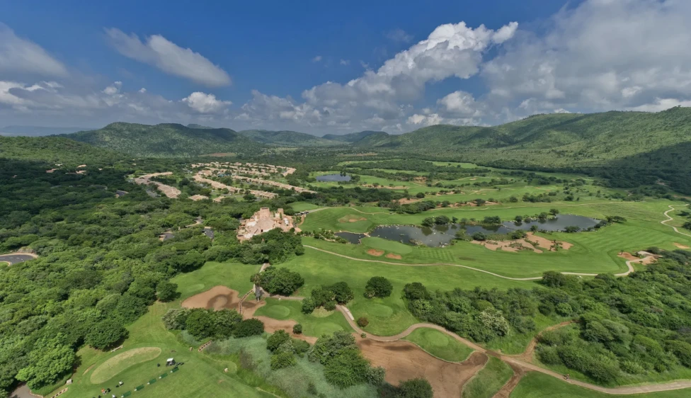 Lost City Golf Club Vista aérea amplia del Lost City Golf Club con lagos, calles verdes y montañas.