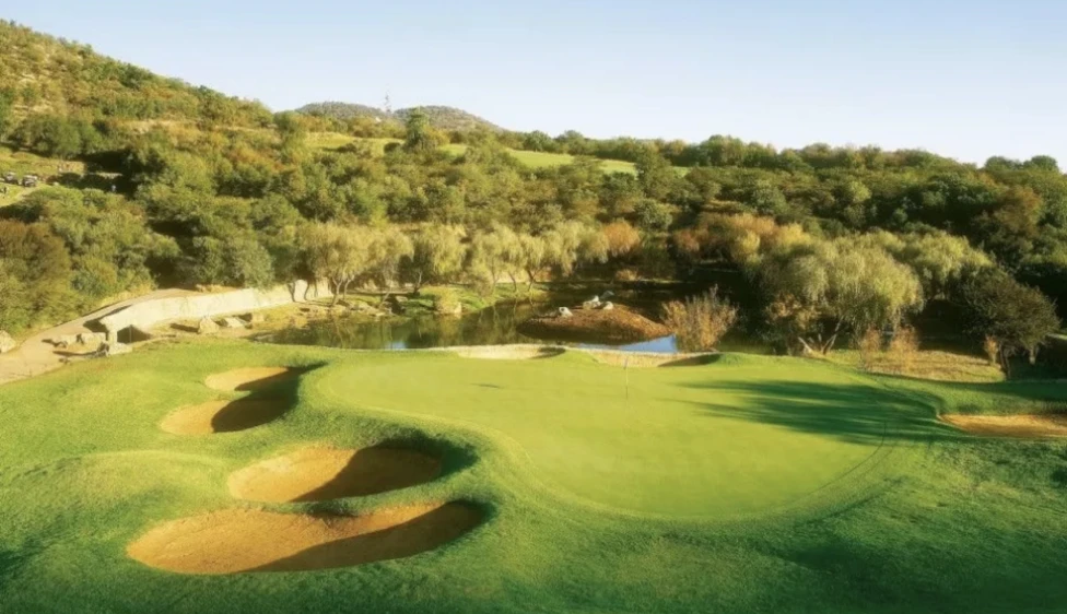 Green del Lost City Golf Club rodeado de búnkeres, agua y vegetación natural.