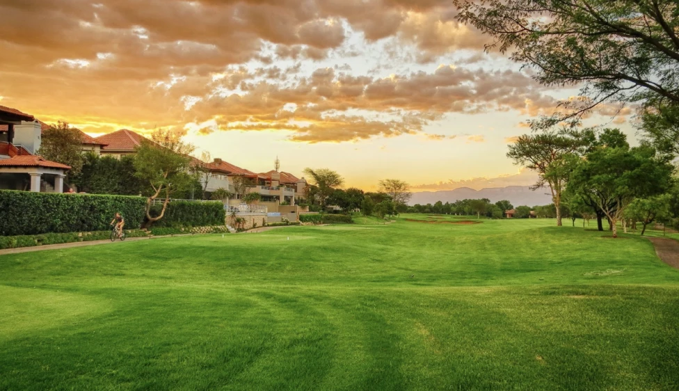 Calle del Pecanwood Country Club junto a residencias, árboles y montañas al atardecer.