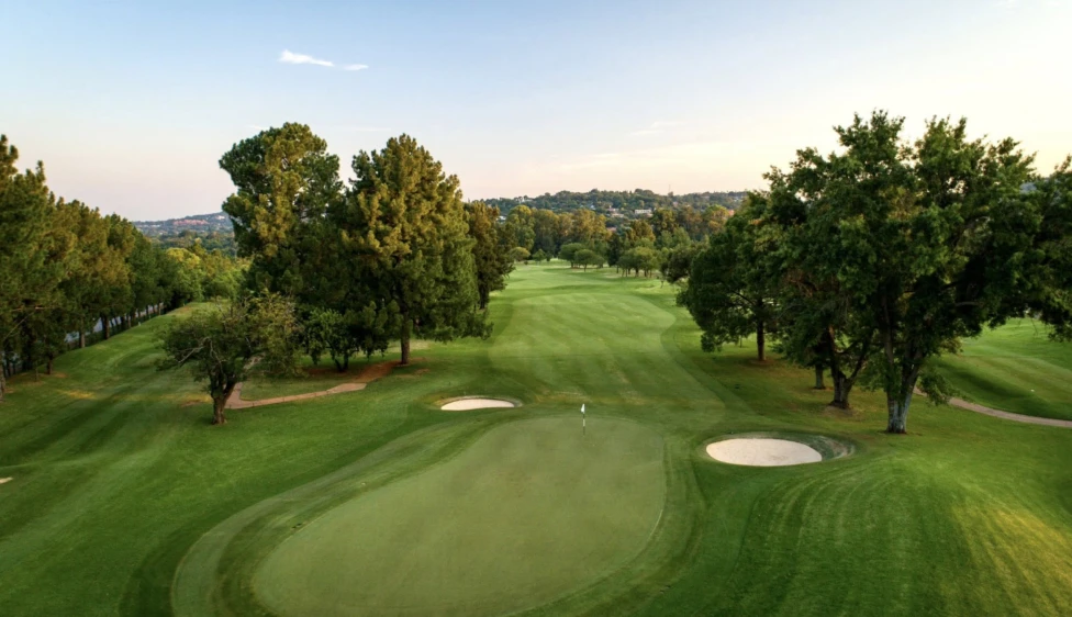 Green del Pretoria Country Club con dos búnkeres, calles verdes y árboles frondosos.