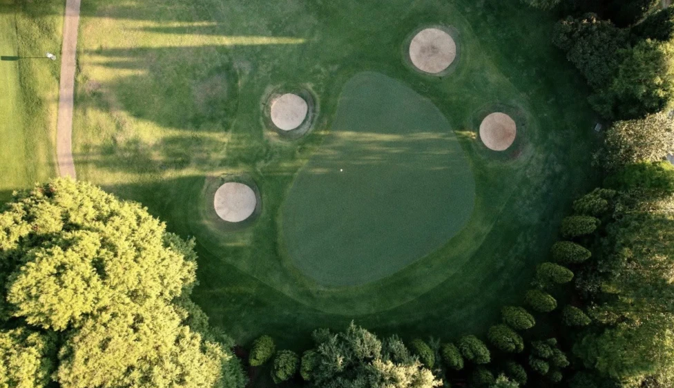 Vista aérea de un green del Pretoria Country Club rodeado de cuatro búnkeres y árboles.